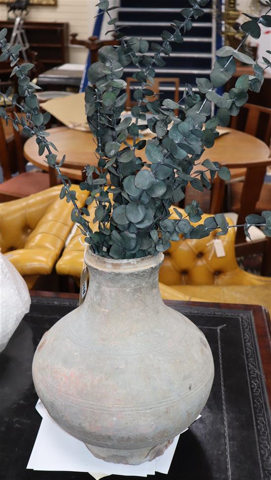 A Middle Eastern clay pot, with artificial plant